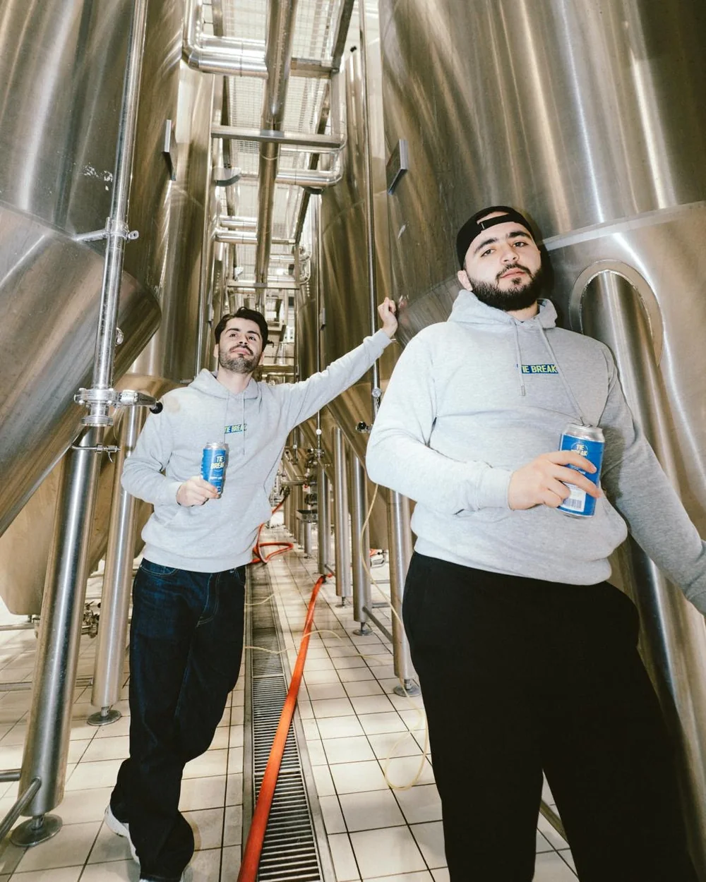 Les deux frères, canette Tie Break à la main, entre les cuves de fermentation de la brasserie